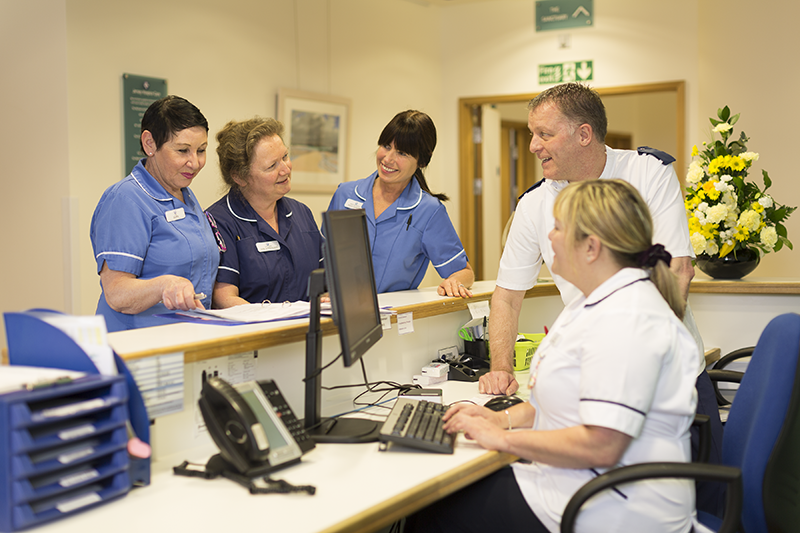 A picture of nurses talking at a desk, at Jersey Hospice Care
